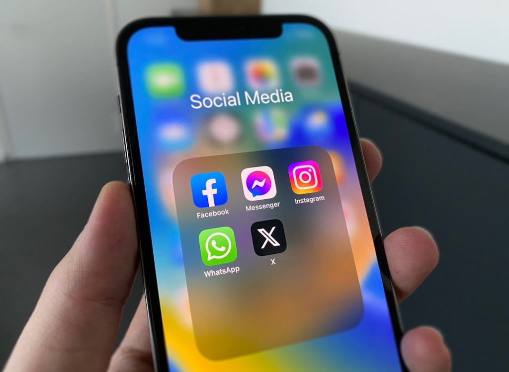 Person holding a cell phone with social media app icons